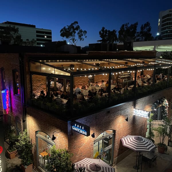 Cafe Santorini's illuminated outdoor patio at night, with diners seated under string lights.